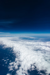 Plane window view with blue sky and beautiful clouds. As seen through window of an aircraft. View of wing & ocean. Airplane from city Bangkok to island Bali.