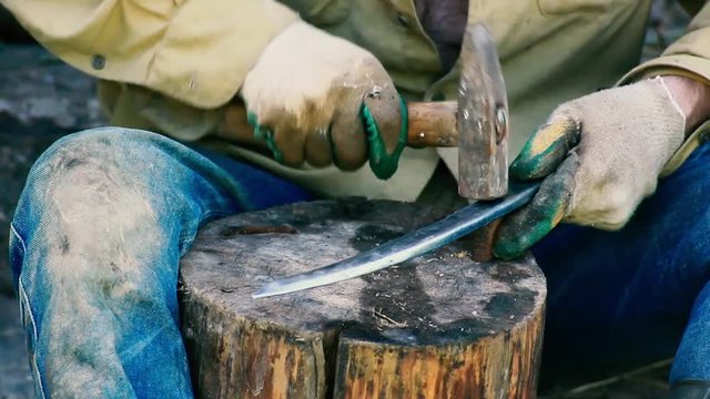 traditional iron forging, artisan sharpens a sharp knife blade with a hammer.