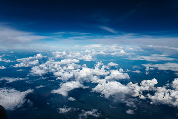 Plane window view with blue sky and clouds. Clouds and sky as seen through window of an aircraft. View of beautiful cloud and city from the airplane.