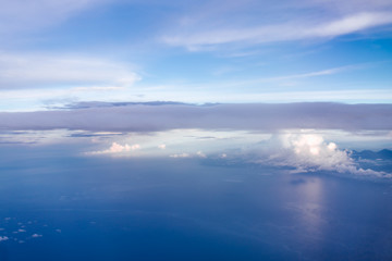 Plane window view with blue sky and clouds. Clouds and sky as seen through window of an aircraft. View of beautiful cloud, ocean and city from the airplane.