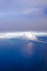 Plane window view with blue sky and clouds. Clouds and sky as seen through window of an aircraft. View of beautiful cloud, ocean and city from the airplane.