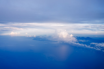 Plane window view with blue sky and clouds. Clouds and sky as seen through window of an aircraft. View of beautiful cloud, ocean and city from the airplane.