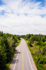 Empty two-lane road passing through forest.