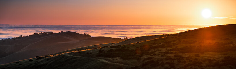 Panoramic view at sunset of valley covered in a sea of clouds in the Santa Cruz mountains, San Francisco bay area, California