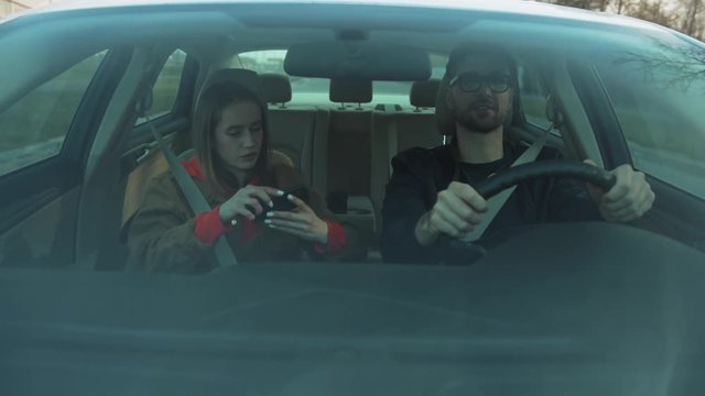 Young driver pointing finger at building. Girlfriend using navigator app on smartphone. Serious girl showing way. Automobile concept, cellphone, innovation, message, communication, holding, automobile