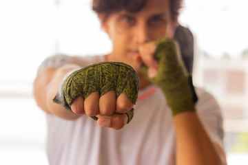 Retrato de hombre en posición de golpe con cintas para guantes de box en gimnasio
