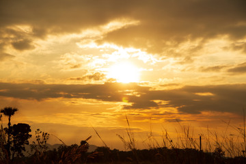 Obraz premium Evening weather, Golden sky and cloud with Light sunshine, Dark shadow meadow in the field and far away as a mountain.