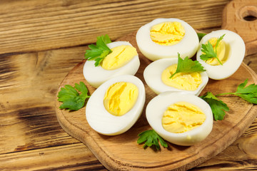 Boiled eggs with parsley on cutting board on a wooden table