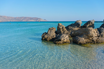 Vacationers enjoy warm shallow waters on a coast of Crete island in Greece.