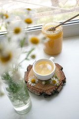 Obraz na płótnie Canvas Cup of herbal tea, honey and chamomile on the white windowsiil, summer tea time, remedy aternative