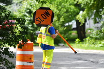 outdoor worker hold slow sign at road construction site - obrazy, fototapety, plakaty