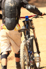 a male cyclist walking with his broken downhill bike after a hard landing