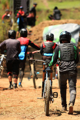 A group of downhill cyclist walking to the finish line with their bikes, cycling equipment