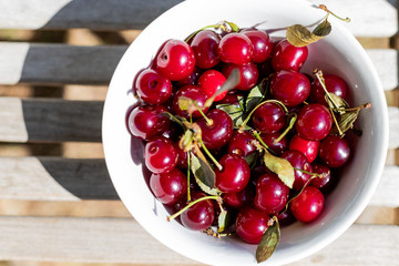 fresh cherry berries in white bowls close-up. background with berries. Organic ripe red cherry berries on wooden background.sweet cherries in garden.