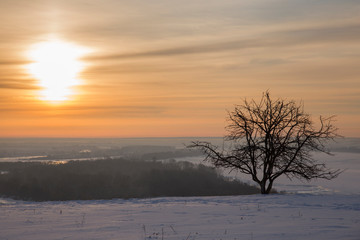 Panoramic view on frozen river and forest on hill in winter during sunset from hill