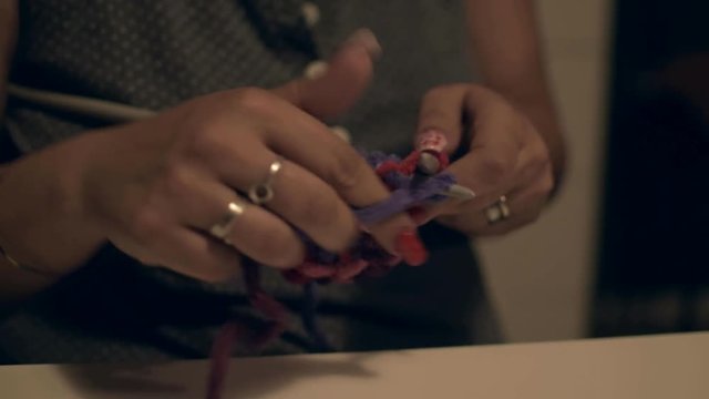 Woman knitting with stitches at home creating a crafty handmade gift.
