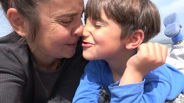 4K Selfie Mother and son pull and rub their faces resting on the beach
