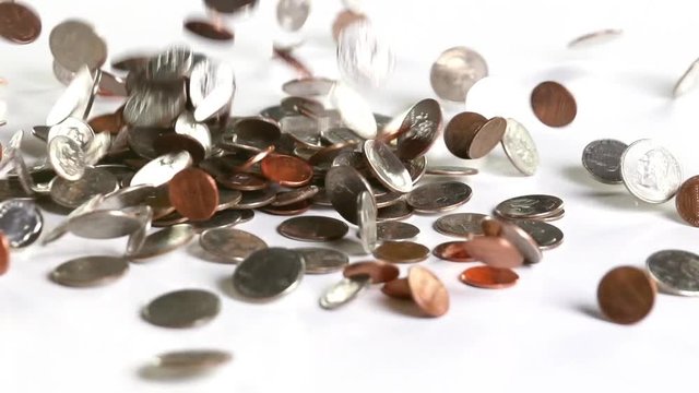 US coins falling onto a white surface in slow motion