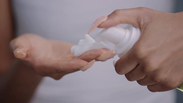 Close-up view of beautiful african black female hands puring facial lotion. Healthy skin and care concept.