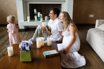 young parents admire their one-year-old daughter, laughing, sitting on the floor