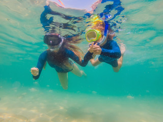 happy mother and son snorkeling in the sea. Look at the fish under water