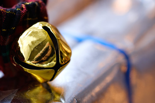 Gold Jingle Bell Sits On A Christmas Wrapped Gift