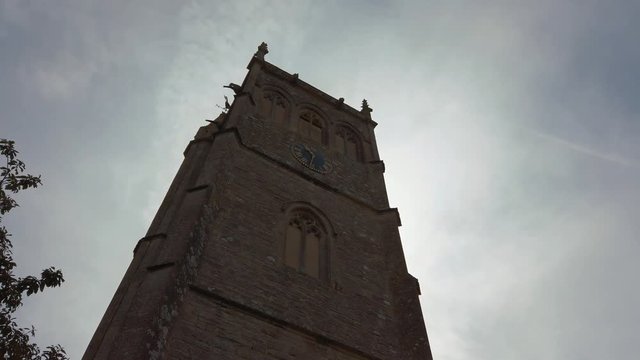 Walking towards tall church bell tower against grey sky
