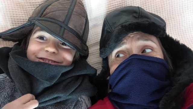 4K Selfie on bed mother and child in winter clothes get cold