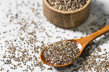 Chia seeds in a wooden bowl on a light background. For healthy nutrition
