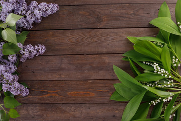 The decor of the flowers of lilies of the valley and lilac on the background of vintage wooden boards. Vintage background with frame of flowers and place under the text. Flat lay. Vintage.