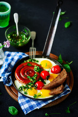 Fried eggs with sausages and green salsa