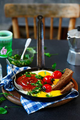Fried eggs with sausages and green salsa