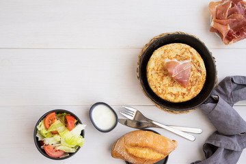 Frying pan with Tortilla, Spanish omelette made with eggs and potatoes and servedwith  jamon,iberian ham..Top view.  .