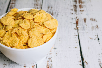 A bowl of cornflakes on the edge of the table