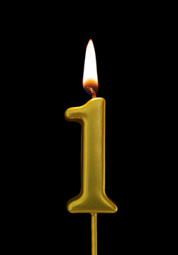 Burning birthday golden candle isolated on black background, number 1