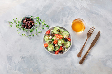 Greek salad. An overhead photo of a plate of fresh salad of feta cheese, cherry tomatoes, cucumbers, onions and olives. A dinner with white wine
