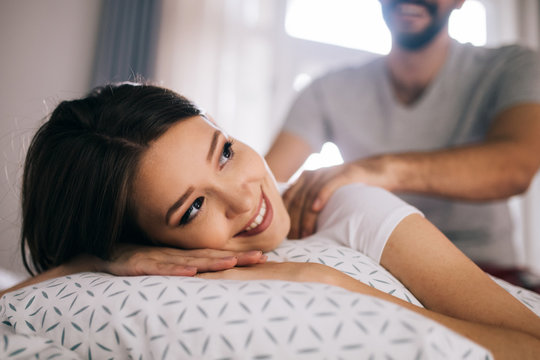 Couple and lovely moments in the bed. Boyfriend giving massage for his beautiful girlfriend