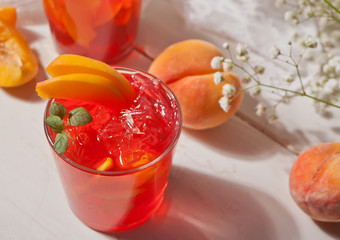Glass with fresh homemade peach sweet iced tea or cocktail, lemonade with mint. Refreshing cold drink. Summer party.