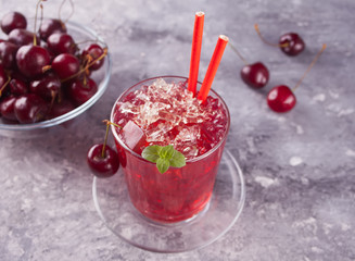 Glass with fresh homemade cherry sweet iced tea or cocktail, lemonade with mint. Refreshing cold drink. Summer party.