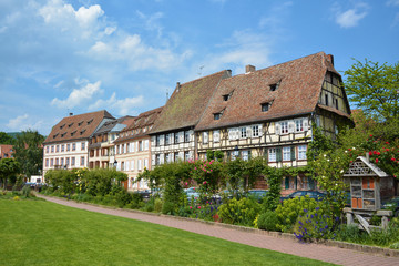 Fototapeta na wymiar Small park with view on beautiful traditional old European style timber framing houses in city center on sunny day in Wissembourg in France