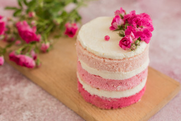 Obraz na płótnie Canvas Beautiful pink cream and berries cake on a light concrete background. Birthday celebration