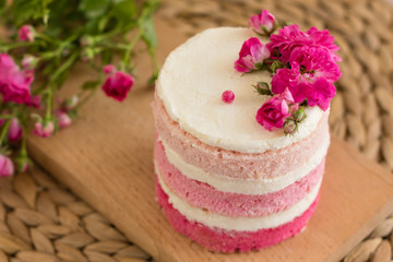 Beautiful pink cream and berries cake on a light concrete background. Birthday celebration