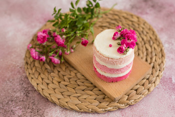 Beautiful pink cream and berries cake on a light concrete background. Birthday celebration