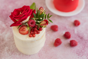 Beautiful pink cream and berries cake on a light concrete background. Birthday celebration