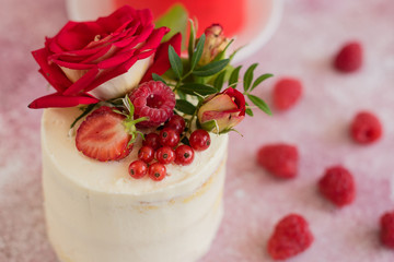 Beautiful pink cream and berries cake on a light concrete background. Birthday celebration