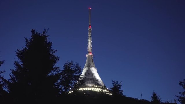 Night shot of Jested Tower with hotel and restaurant, sliding right with trees in foreground, beautiful cinematic view, Czech Republic