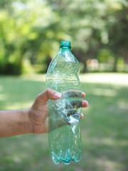 A man carrying the crumpled bottle of the water in the forest. Garbage collection in the forest by volunteers. Don't dump plastic