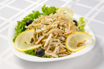 fried squid with onions and lettuce, garnished with lemon and olives