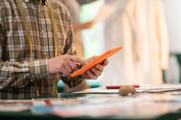 Close-up photo of man holding a tablet in hands