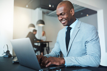 Smiling young African American businessman working on a laptop